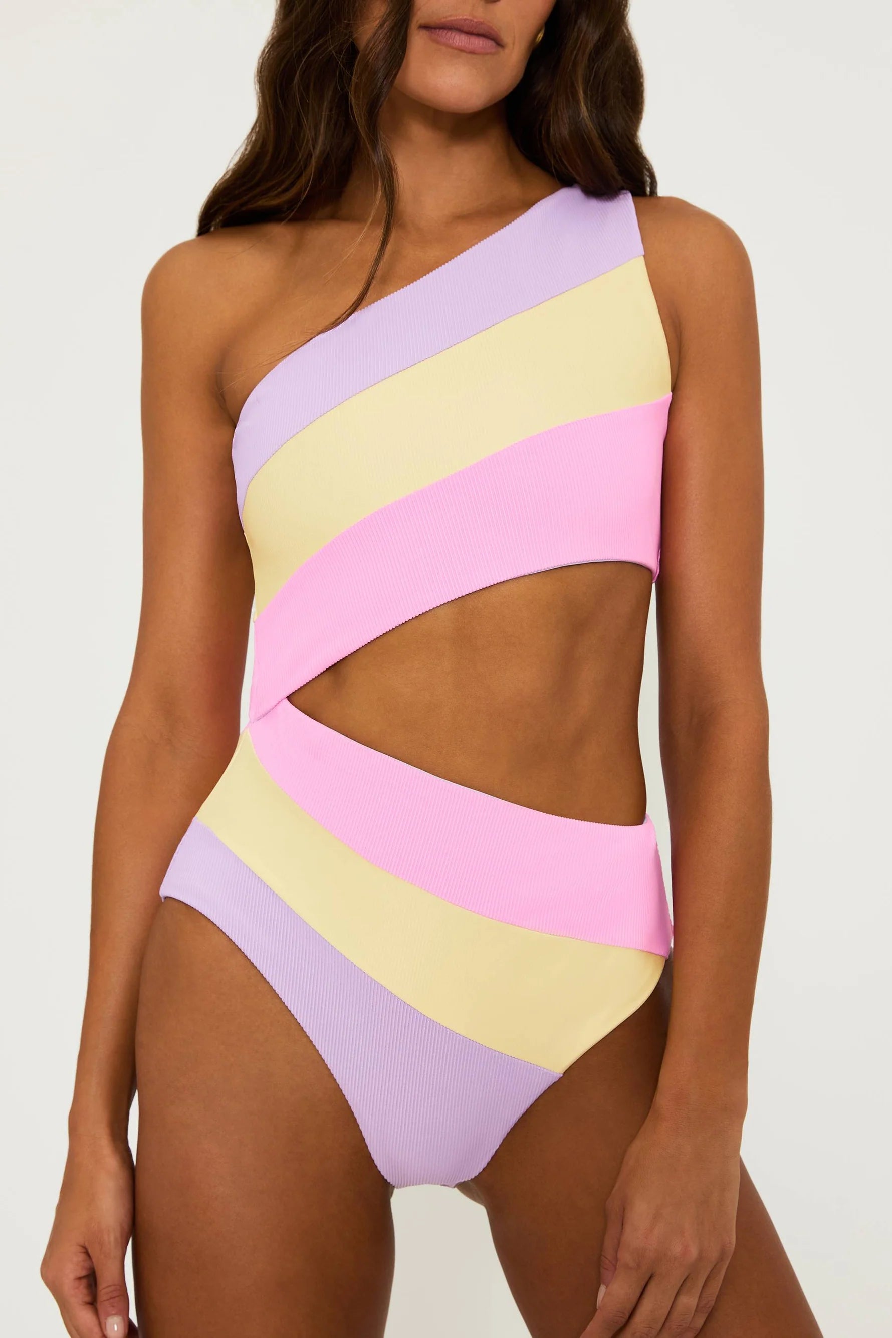 Asymmetric one piece with one shoulder strap and side cutout in pink, yellow, and lavender color block
