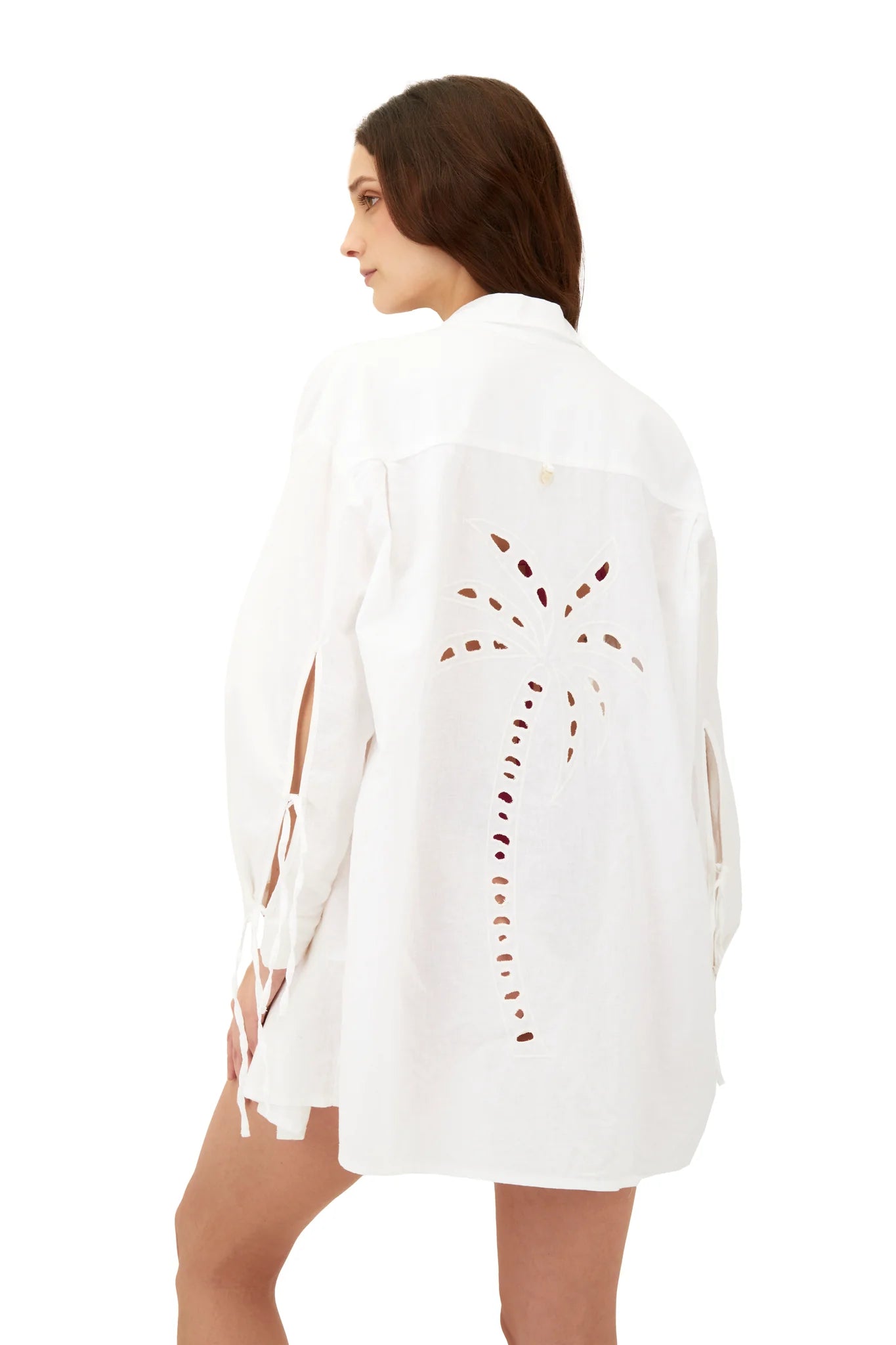 White collared shirt with buttons down the front, ties on the sleeves, and an eyelet palm tree design on the back.