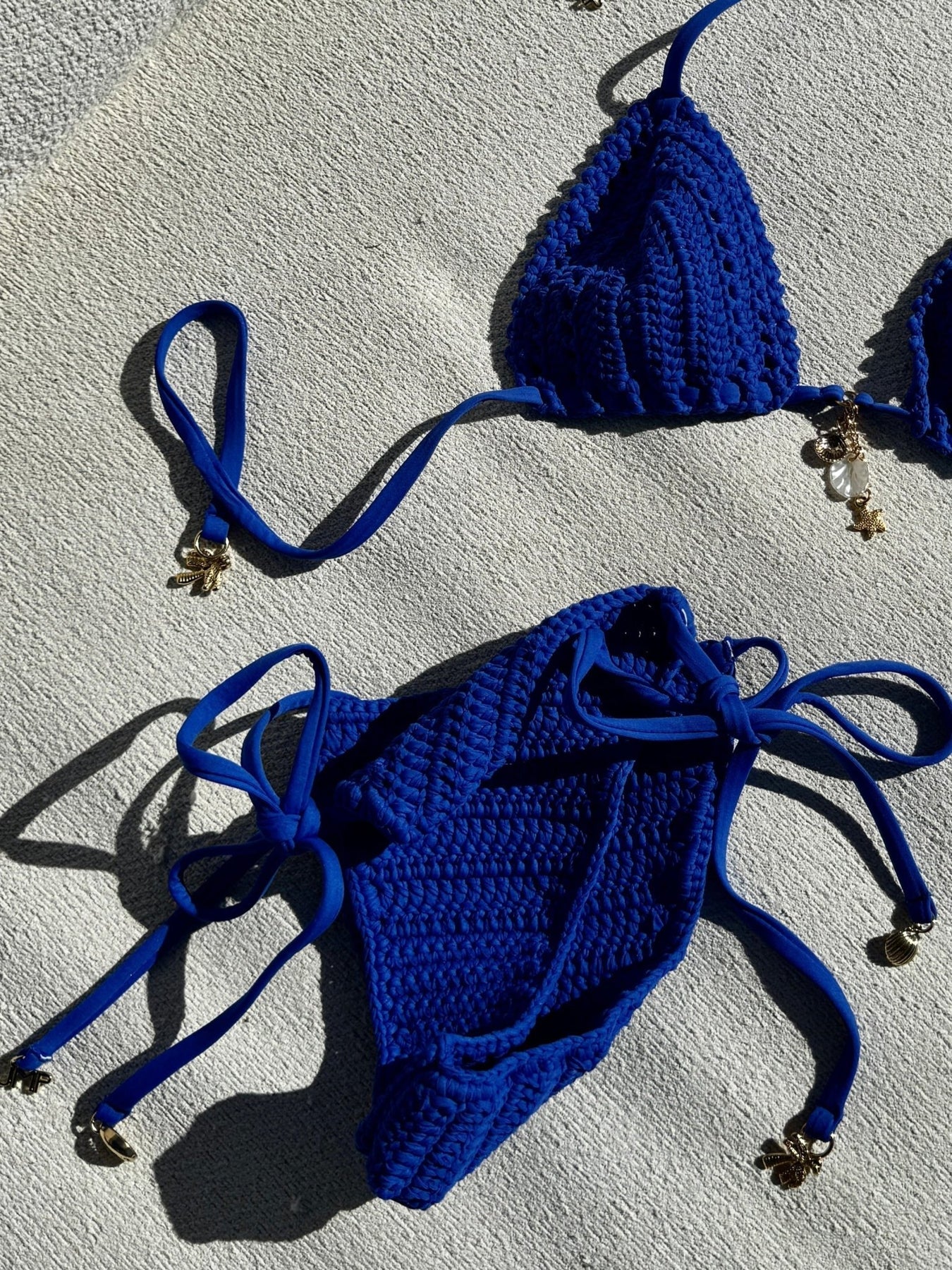 Skimpy crochet bottom with tie sides adorned with gold shells. Available in Cobalt.