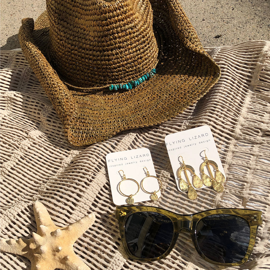 various fashion accessories including a cowboy beach hat, earrings, and sunglasses 