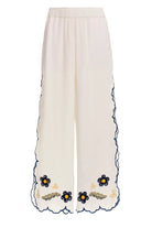 White wide leg pants with elastic waistband and blue and yellow embroidered floral print