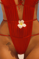 Red one piece with a deep plunging neckline, open back and sides, and skimpy coverage in the back