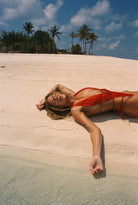 Red one piece with a deep plunging neckline, open back and sides, and skimpy coverage in the back