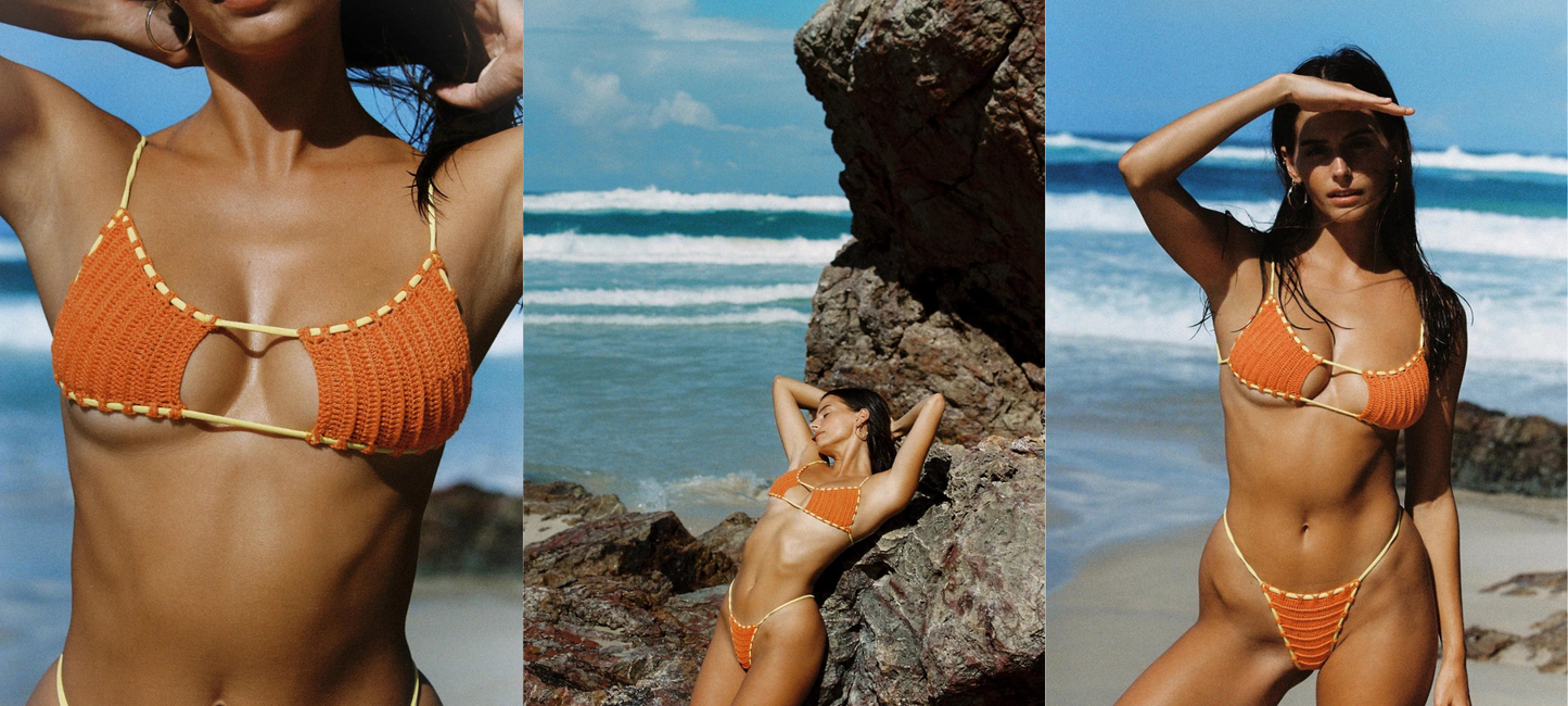 Web banner showcasing 'Shop New Indah Arrivals' with images of a model wearing an orange crochet bikini. The model is posing on a beach with clear blue skies and rock formations in the background, evoking a summer feel. A 'Shop Now' button is prominently displayed to invite browsing and shopping.